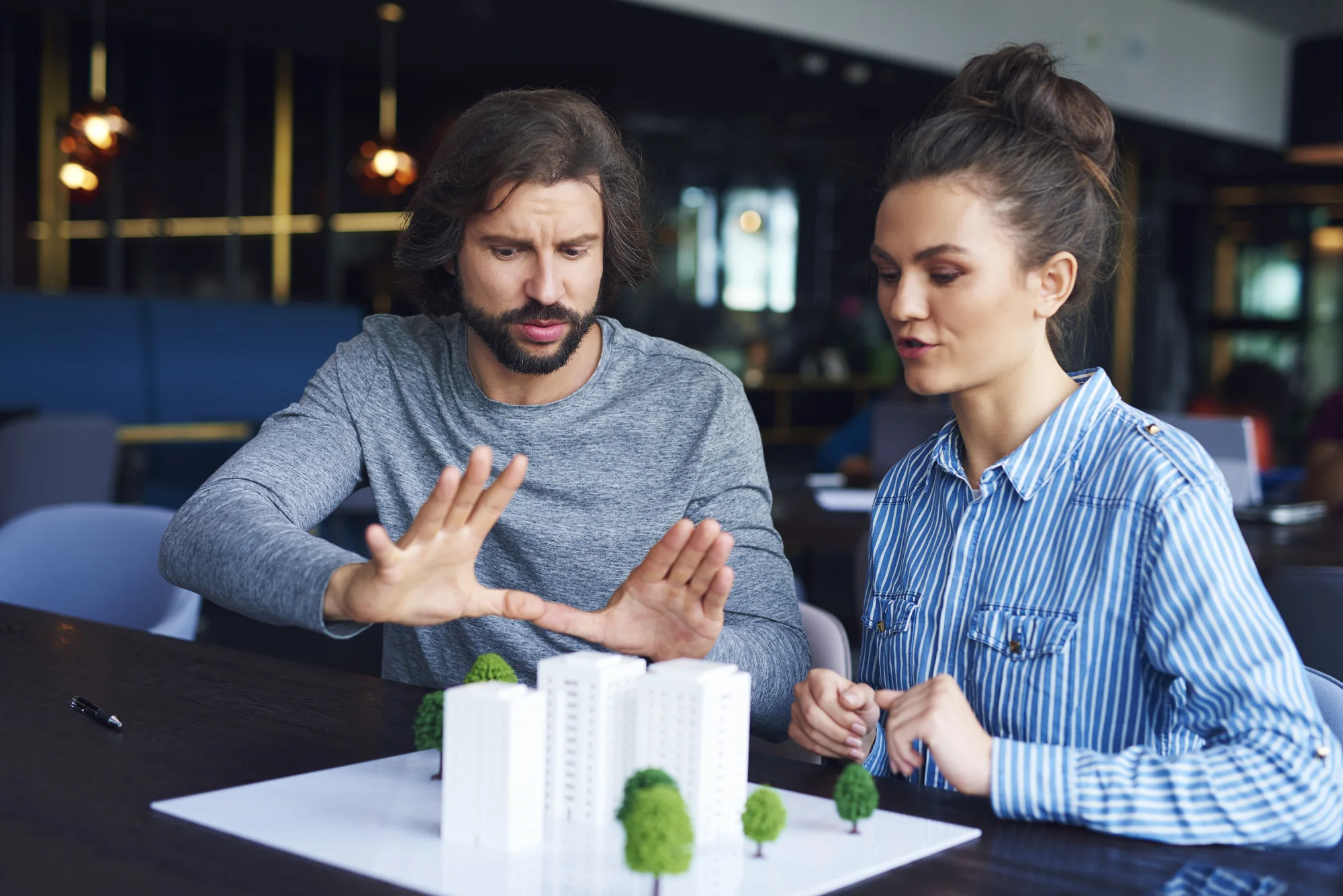 Two colleagues discussing an architectural model at a table